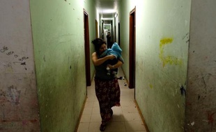 Une femme Rom, son enfant dans les bras, dans un couloir du camp "Best House", le 10 novembre 2014 à Rome
