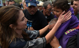 La reine Rania de Jordanie (G) tente de réconforter des migrants sur l'île grecque de Lesbos, le 25 avril 2016