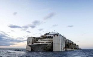 L'épave du paquebot Concordia à son entrée le 27 juillet 2014 dans l'enceinte du terminal Europe de Voltri, en banlieue de Gênes, tirée par plusieurs remorqueurs