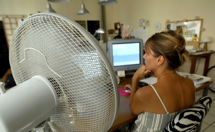 Une personne travaille à côté d'un ventilateur, le 07 août 2003