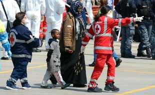 Des membres de la Croix Touge escortent des migrants qui arrivent dans le port de Messine, en Sicile, le 15 avril 2015