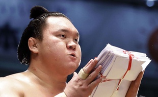 Le champion mongol de sumo Hakuho reçoit une liasse d'enveloppes contenant de l'argent des sponsors après avoir remporté un combat à Nagoya, le 23 juillet 2017.