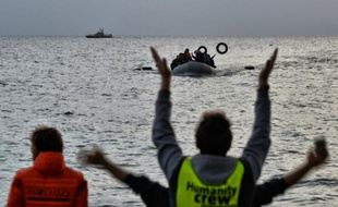 Des militants d'une ONG guident des migrants arrivant à bord d'un bateau arrivant de Turquie à Mytilène sur l'île grecque de Lesbos le 19 février 2016