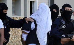 Yassin Salhi entre des policiers lors de la perquisition à son domicile le 28 juin 2015 à Saint-Priest