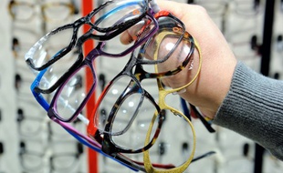 Photo d'illustration d'un opticien tenant des paires de lunettes dans sa main.