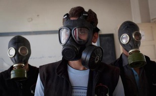Des hommes portent des masques à gaz lors d'une simulation d'attaque chimique, dans le nord de la Syrie, en mars 2014