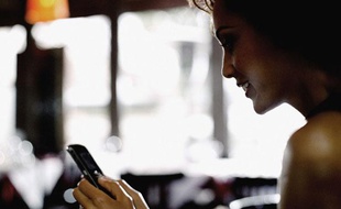 Une femme utilise son smartphone au restaurant.