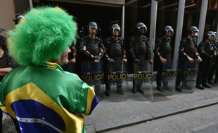 Un supporter brésilien devant la police anti-émeute, le 9 juin 2014, à Sao Paulo.
