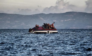 Des migrants et réfugiés appellent à l'aide alors que leur bateau est en train de couler près des côtes de l'île grecque de Lesbos, le 30 octobre 2015 en mer Egée