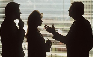 Deux hommes et une femme discutent dans un bureau.