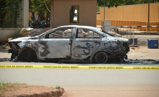 Cette photo prise le 3 mars 2018 à Ouagadougou montre une voiture incendiée devant l'ambassade de France, un jour après des attaques terroristes. AFP PHOTO / Ahmed OUOBA