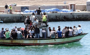 Un bateau de migrants arrive sur l'île italienne de Lampedusa, le 1er août 2011. Sur le quai sont allongés les corps de 25 migrants africains qui tentaient de rejoindre l'Italie depuis la Libye.