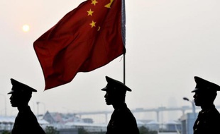 Des militaires chinois passent devant le drapeau national, le 31 octobre 2010 à Shanghai