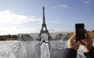 Un homme saute devant le trompe-l'œil créé par l'artiste JR devant la tour Eiffel.