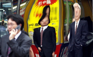 Des «salarymen» japonais reflétés dans une vitrine à Tokyo.