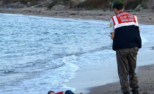 Un policier turc se tient près du corps d'un enfant migrant mort noyé, sur une plage de Bodrum, au sud de la Turquie, après le naufrage d'un bateau transportant des réfugiés, le 2 septembre 2015