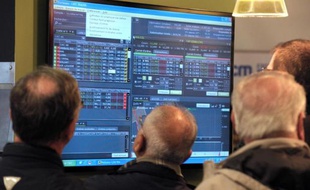 Des personnes regardent les cours de la Bourse sur un écran