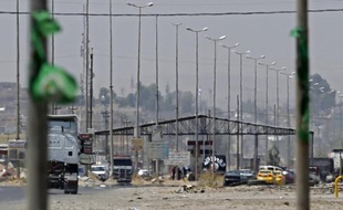 Des jihadistes de l'EIIL tiennent un point de contrôle à l'entrée de Mossoul, le 16 juin 2014