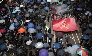 Des manifestants pro-démocratie défilent avec un drapeau chinois et ses étoiles dorées en forme de croix gammée dans le centre de Hong Kong, samedi 31 août 2019.