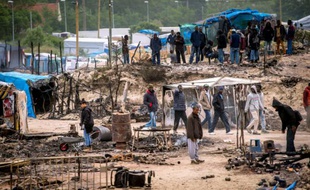 Des migrants s'activent pour remettre de l'ordre dans la "Jungle" de Calais le 27 mai 2016 au lendemain d'une importante rixe qui a fait 40 blesséz