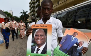 Un homme pose avec des affiches montrant le président Alassane Ouattara à Abidjan, le 25 avril 2015