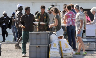 Des migrants reçoivent une aide alimentaire d'une ONG, à Calais.