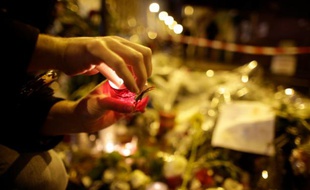 Une personne allume une bougie le 20 novembre 2015 à Paris en face du restaurant "La Casa Nostra", où cinq personnes ont été tuées il y a une semaine