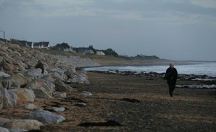 Un homme marche près d'une digue à Barneville-Carteret le 8 décembre 2015