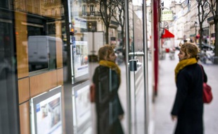 Une femme scrute les annonces de location dans la vitrine d'une agence immobilière, le 18 mars 2013 à Paris