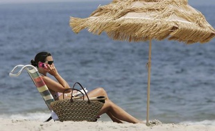 Vacancière qui téléphone sur la plage.