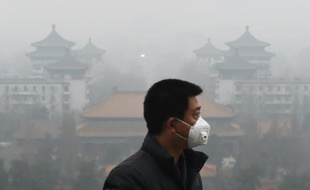 Un homme porte un masque pour se protéger de l'épais brouillard toxique qui submerge Pékin, le 8 décembre 2015