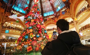 Un homme prend en photo une décoration de Noël dans un centre commercial à Paris.