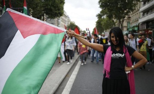 Une manifestante portant le drapeau palestinien durant la manifestation pro-Gaza à Paris qui a réunit plusieurs milliards de personnes samedi 9 aout 2014