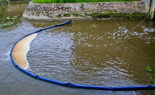 Un barrage flottant pour contenir la pollution sur une rivière. Illustration.