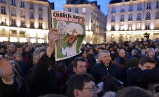 A man holds up an edition of Charlie Hebdo magazine as people gather on the Place Royale in Nantes, western France, on January 7, 2015, to show their solidarity for the victims of the attack by unknown gunmen on the offices of the satirical weekly Charlie Hebdo. Heavily armed men shouting "Allahu Akbar" stormed the Paris headquarters of a satirical weekly on January 7, killing 12 people in cold blood in the worst attack in France in decades. AFP PHOTO / GEORGES GOBET