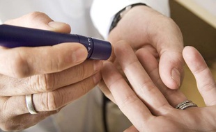 Un médecin prélève une goutte de sang au bout du doigt d'une patiente.