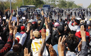 Des manifestants protestent devant une route bloquée par la police anti-émeutes à Mandalay, deuxième ville de Birmanie.