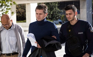 Alexander Vinnik (au centre), escorté par la police grecque, en décembre 2017, peu après son arrestation.