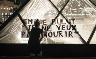 Une femme colle des affiches contre les féminicides sur la pyramide du Louvre à Paris, le 14 septembre 2019.