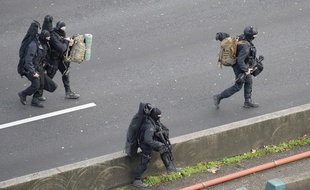 Members of the French police special force RAID walk with their equipment on the "peripherique" (circular road) in Saint-Mande, near Porte de Vincennes, eastern Paris, on January 9, 2015 to take their positions after at least one person was injured when a gunman opened fire at a kosher grocery store on January 9, 2015 and took at least five people hostage, sources told AFP. The attacker was suspected of being the same gunman who killed a policewoman in a shooting in Montrouge in southern Paris on January 8. AFP PHOTO / ERIC FEFERBERG