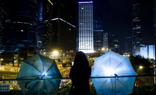 Une femme se tient entre deux parapluies, devenus symboles des manifestants prodémocratie, le 5 octobre 2014 à Hong Kong