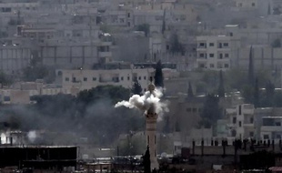 De la fumée s'élève d'un minaret après une nouvelle salve de bombardements sur la ville kurde de Kobané, le 13 octobre 2014