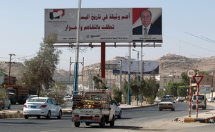 Sanaa (Yémen), le 22 février 2015. Des yéménites entrent dans la capitale en passant devant une affiche du président Abedrabbo Mansour Hadi.