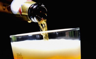 Une personne sert un verre de bière.