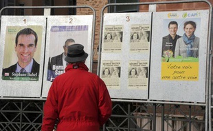 Une personne regarde des affiches électorales sur des panneaux, le 16 mars 2011 à Rodez, en vue des élections cantonales.