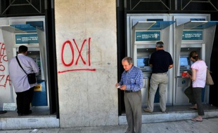 Des Grecs retirent de l'argent à un distributeur, le 2 juillet 2015, à Athènes