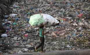 Un homme portant sur son dos un sac de déchets plastique, le 30 mai 2018, dans un bidonville de New Delhi (Inde).