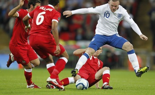 Wayne Rooney se faisant tacler par un défenseur gallois lors d'un match Angleterre-Pays de Galles disputé le 6 septembre 2011 à Londres.