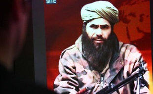 Un homme regarde l'image d'Abdelmalek Droukdel, chef d'Al-Qaida au Maghreb Islamique (Aqmi), le 19 novembre 2010 à Paris.