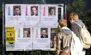 Deux jeunes observant les portraits des candidats à la Présidentielle de 2012 accompagnés d'un message de sensibilisation aux risques du VIH